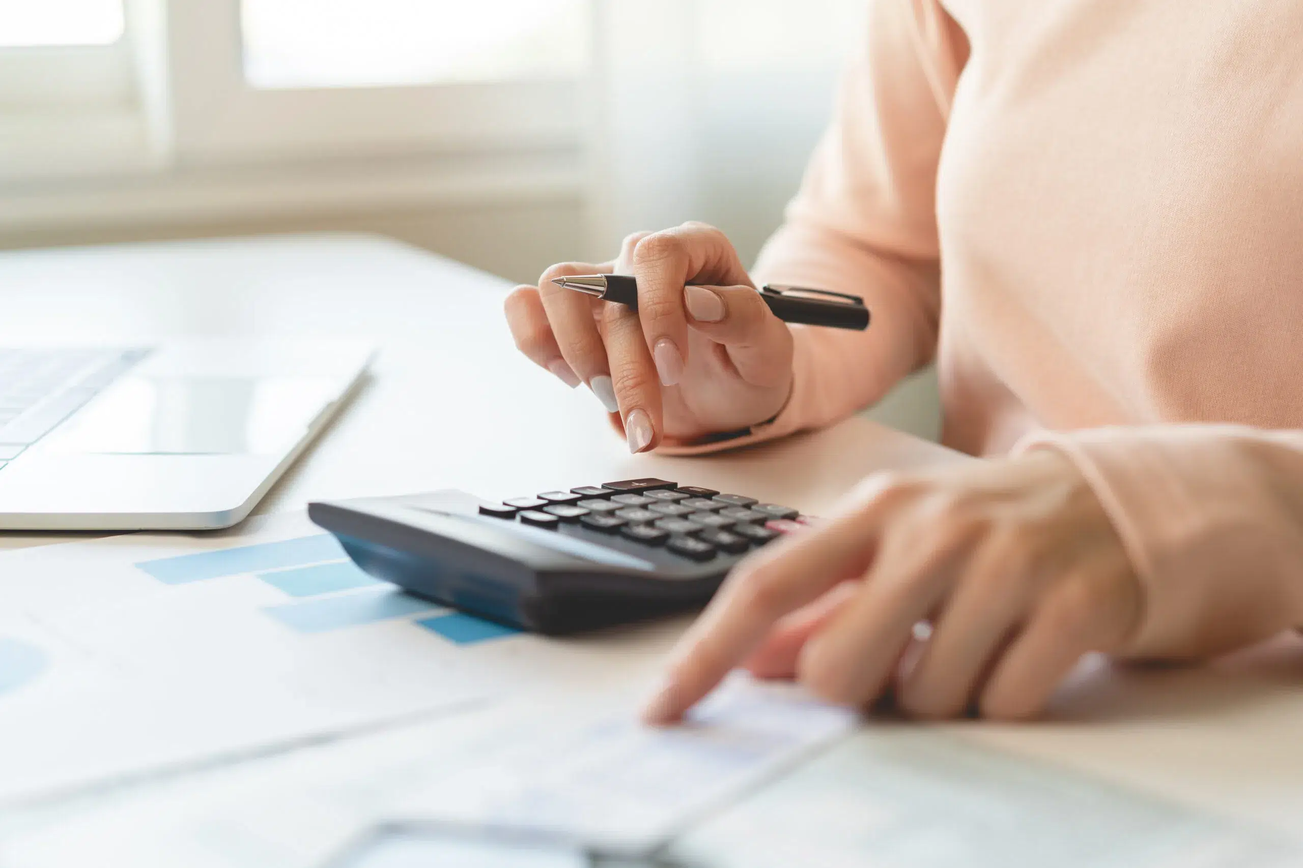 Femme retraitée assise à une table, utilisant une calculatrice pour estimer le montant net de sa pension