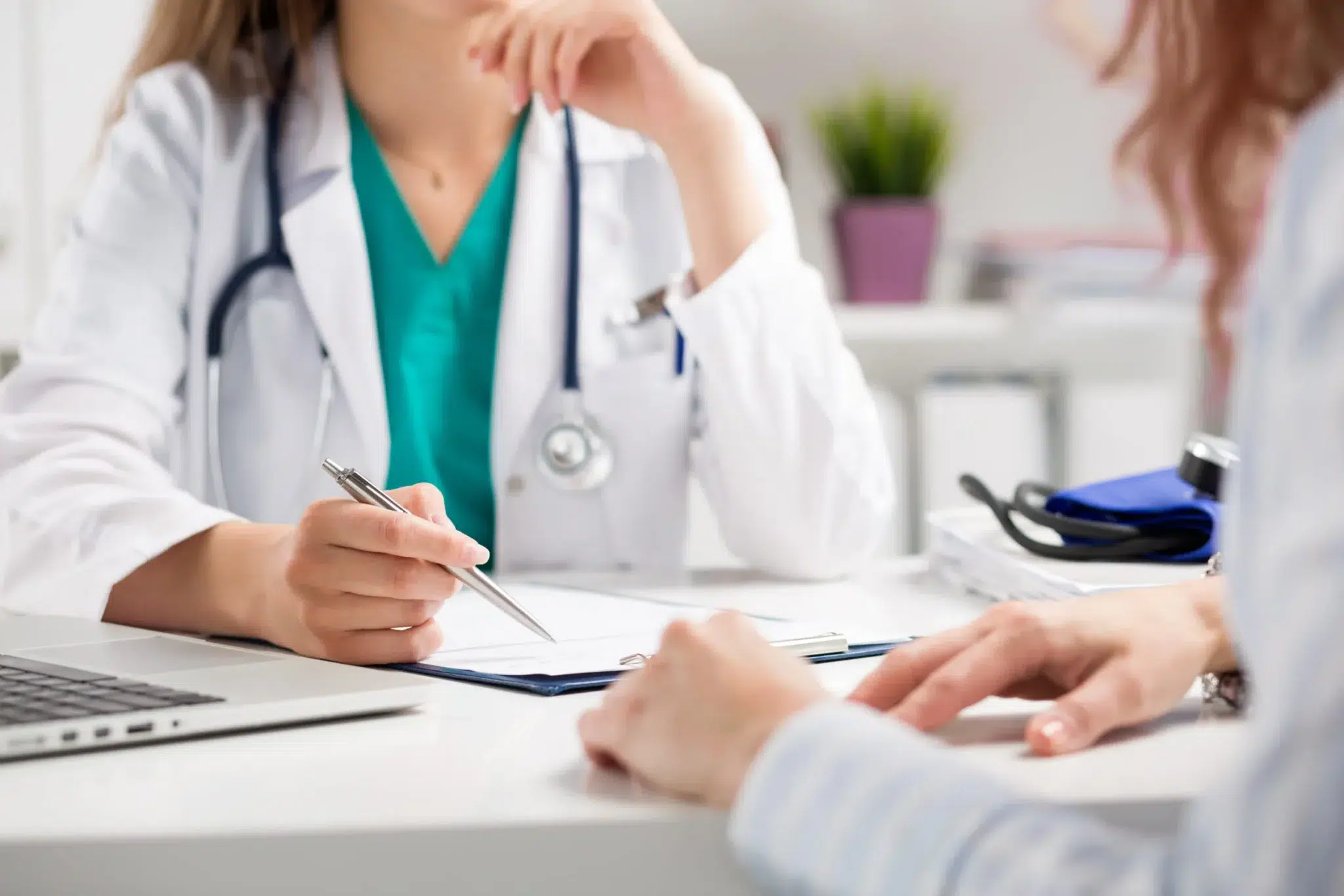 Médecin libéral âgé en blouse blanche en consultation avec un patient dans son cabinet, dans le cadre d’un cumul emploi-retraite.