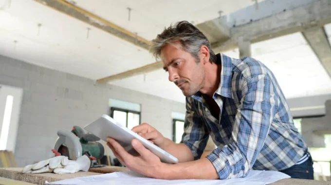 Artisan Sur Un Chantier Consultant Un Plan De Construction – Retraite Des Indépendants, Artisans Et Commerçants : Règles, Calcul, âge De Départ Et Optimisation