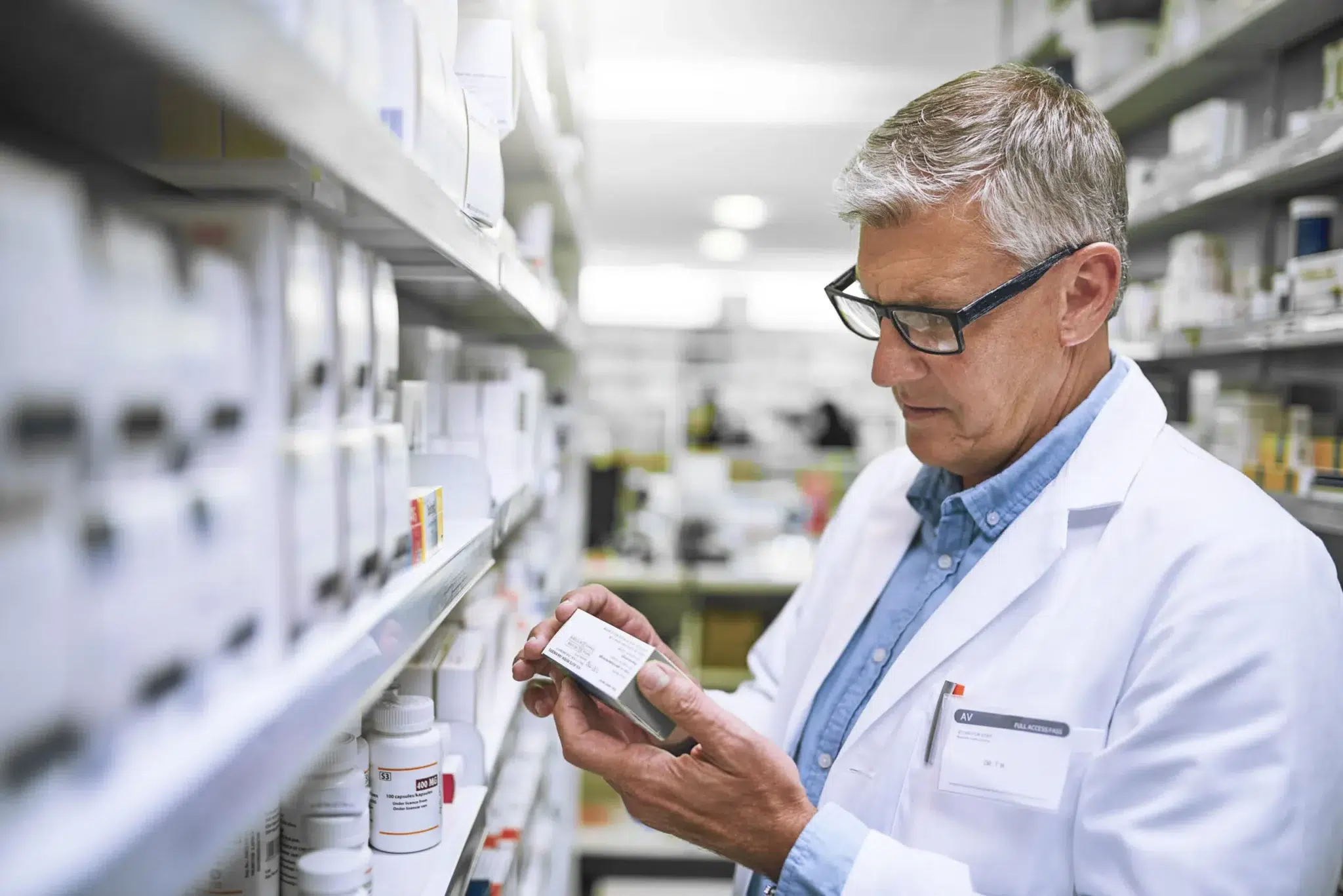 Retraite du pharmacien libéral en 2025 : un pharmacien en officine cherchant une boîte de médicaments
