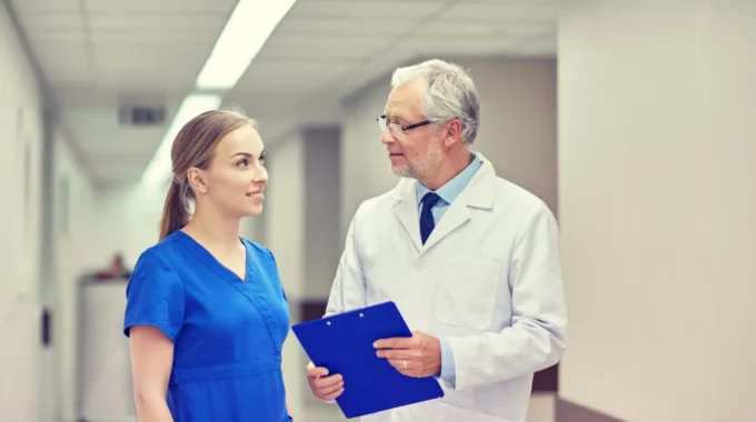 Praticien Hospitalier échangeant Avec Une Infirmière Dans Un Service Hospitalier, Illustrant Les Règles Et Le Calcul De La Retraite Des Praticiens Hospitaliers.