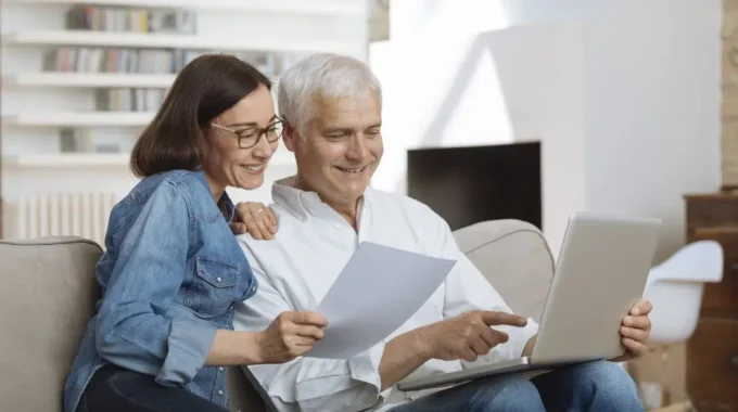 Couple Consultant Un Rapport De Bilan Retraite Sur Un Ordinateur Portable à Domicile