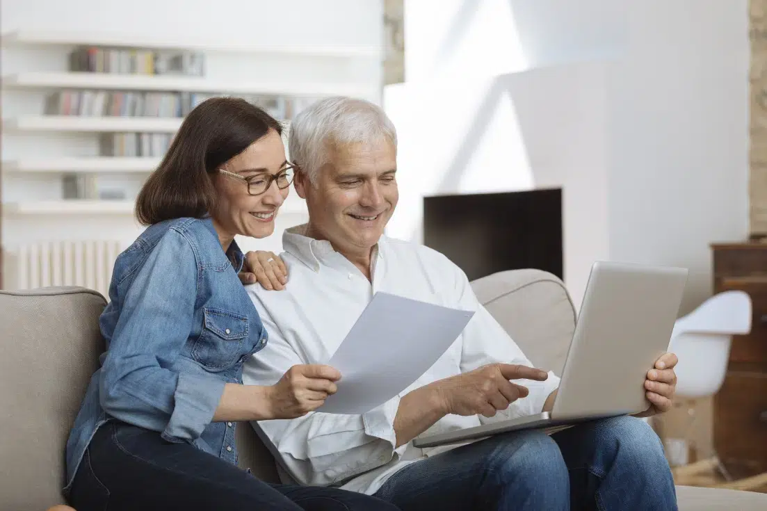 Couple consultant un rapport de bilan retraite sur un ordinateur portable à domicile
