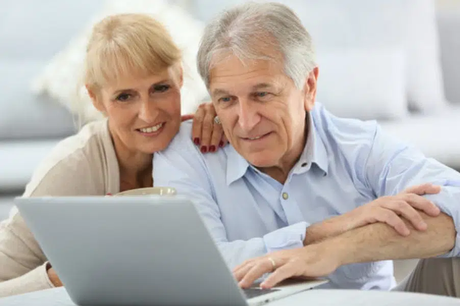Couple consultant leur éligibilité au départ anticipé pour carrière longue sur un ordinateur.
