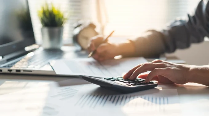 Décote Retraite : Calcul De La Pension Avec Une Main Sur Une Calculatrice
