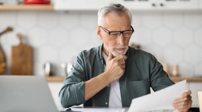 Homme Senior Réfléchissant Devant Son Ordinateur Au Nombre De Trimestres Nécessaires Pour La Retraite à Taux Plein