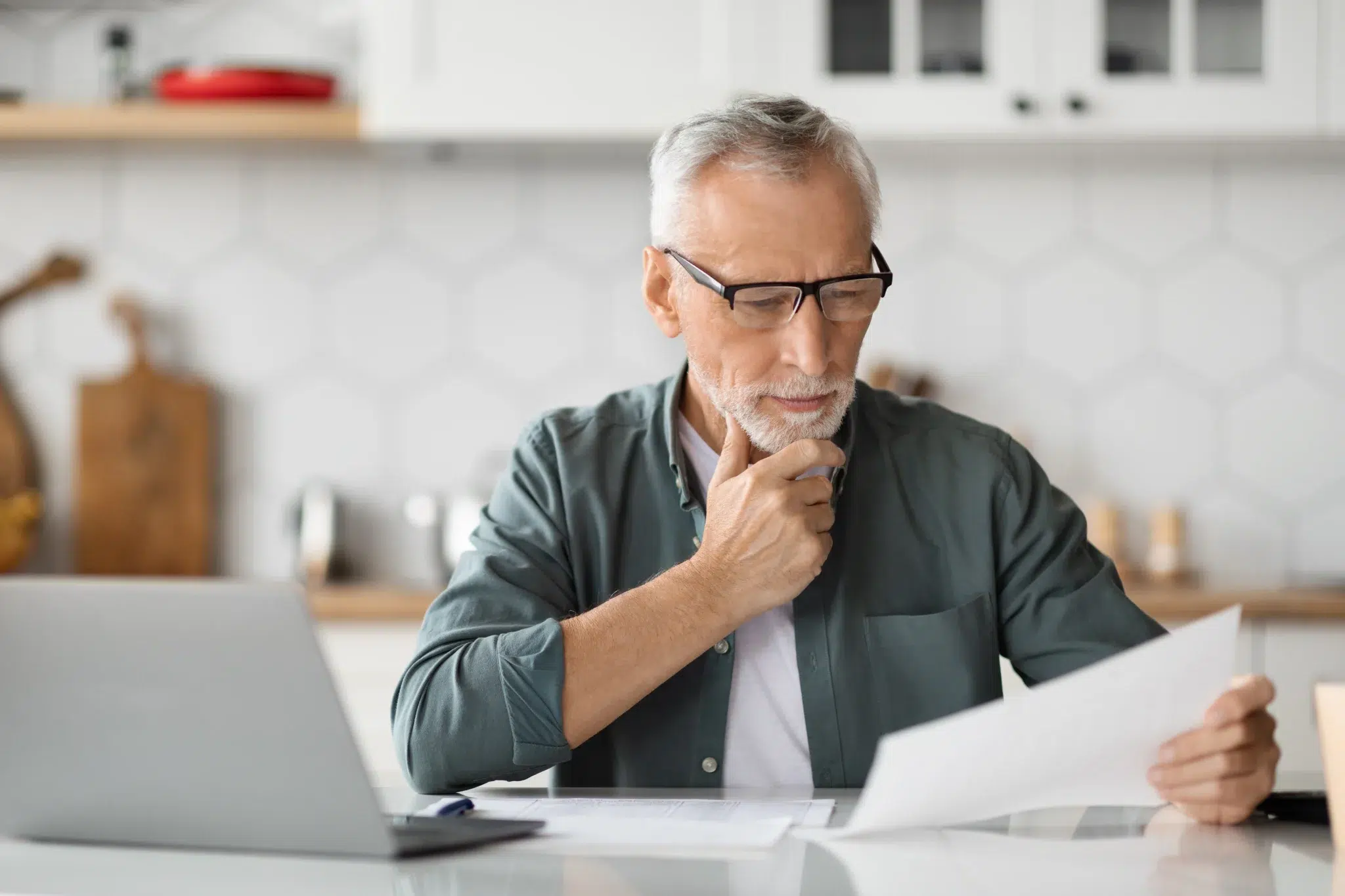 Homme senior réfléchissant devant son ordinateur au nombre de trimestres nécessaires pour la retraite à taux plein