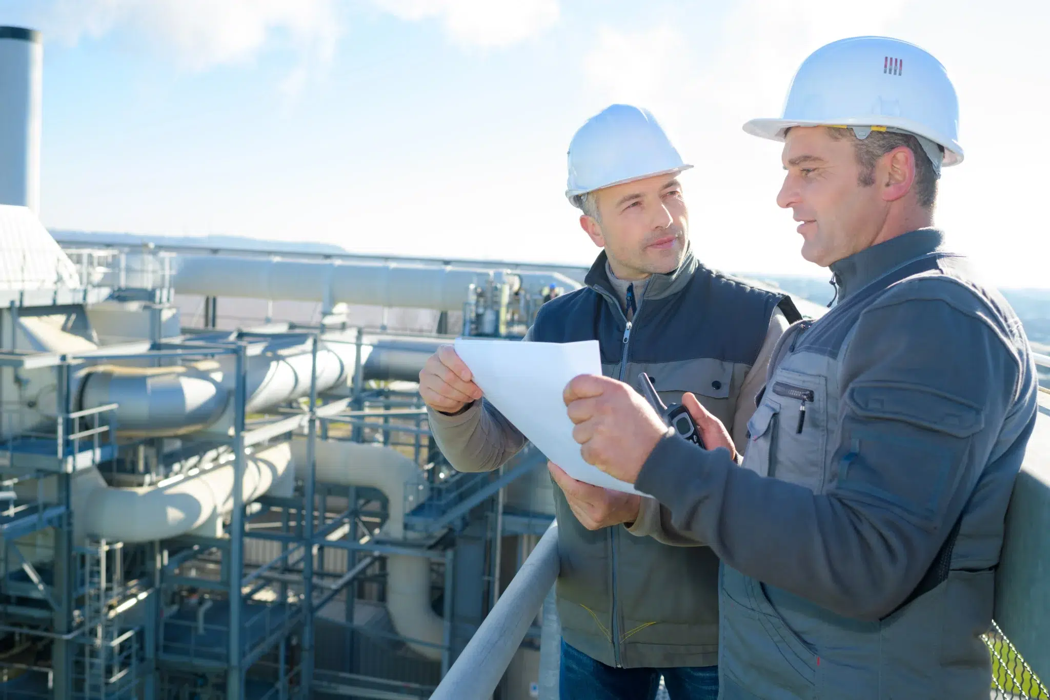 Deux cadres des industries chimiques discutant devant une installation industrielle – départ à la retraite selon la convention collective de la chimie IDCC 44.