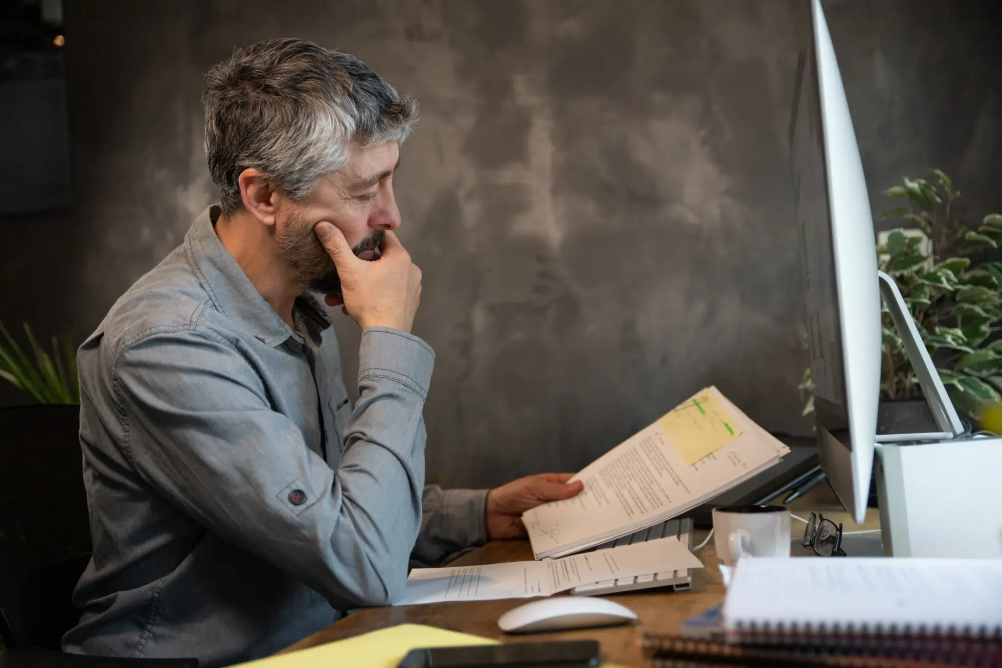 Salarié senior examinant des documents à son bureau et réfléchissant au cumul emploi-retraite