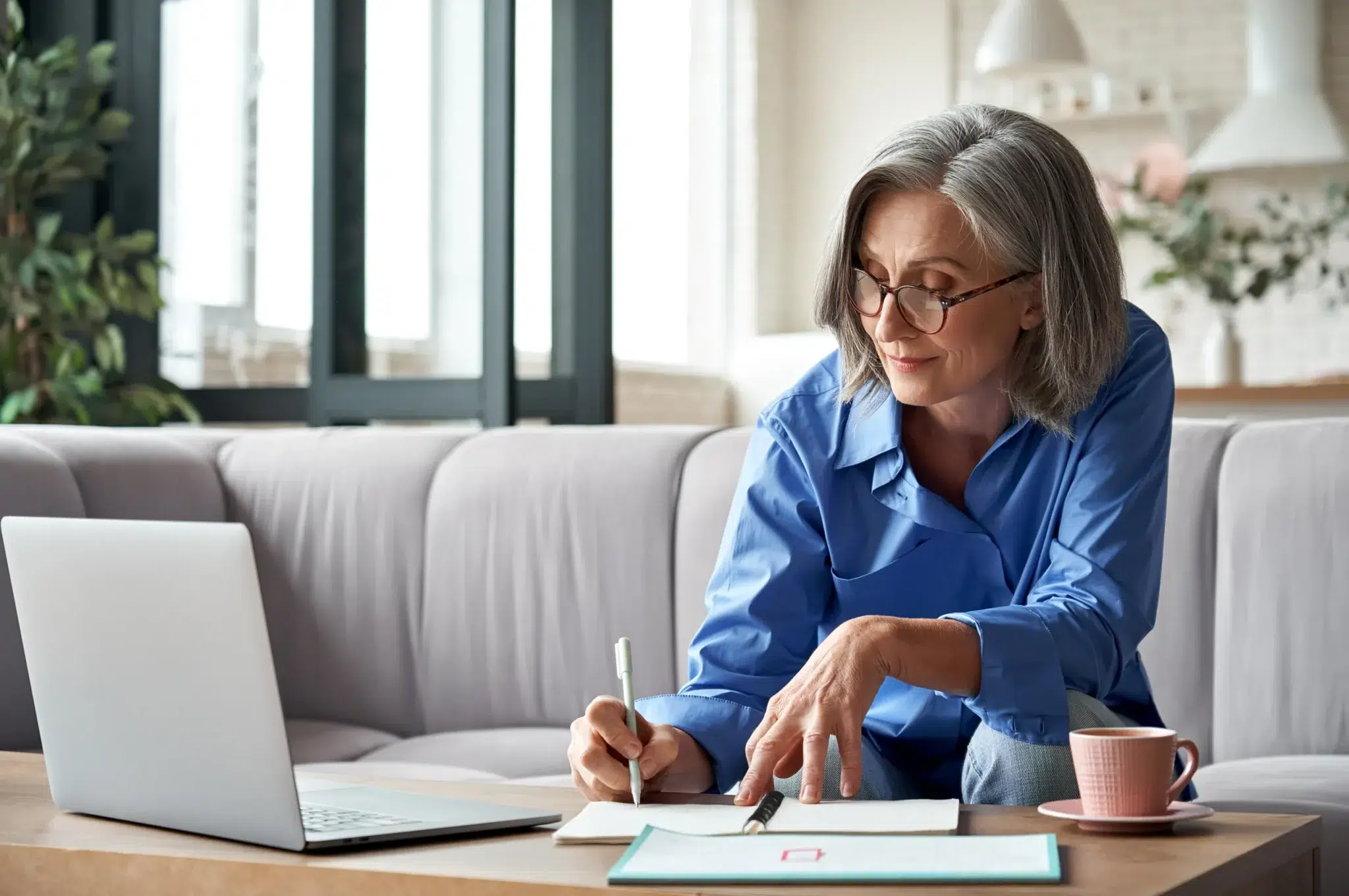 Femme senior prenant des notes devant son ordinateur pour évaluer l'impact d'un congé de reclassement sur sa retraite
