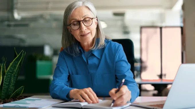 Salariée D'une Soixantaine D'années Rédigeant Une Demande De Retraite Progressive à Son Poste De Travail